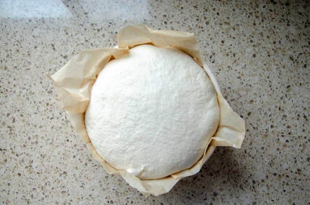 proofed sourdough bread dough in a parchment lined proofing basket