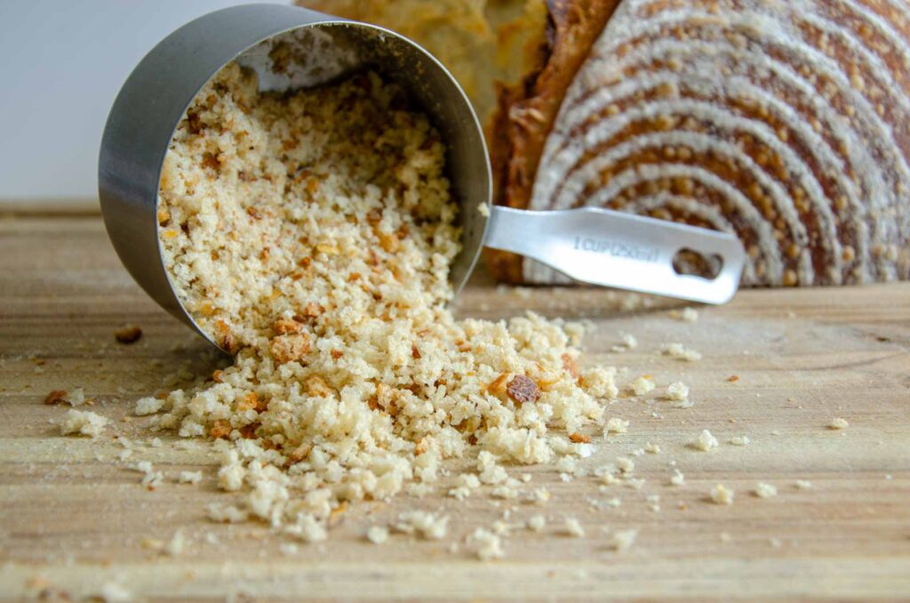 Metal measuring cup full of sourdough bread crumbs