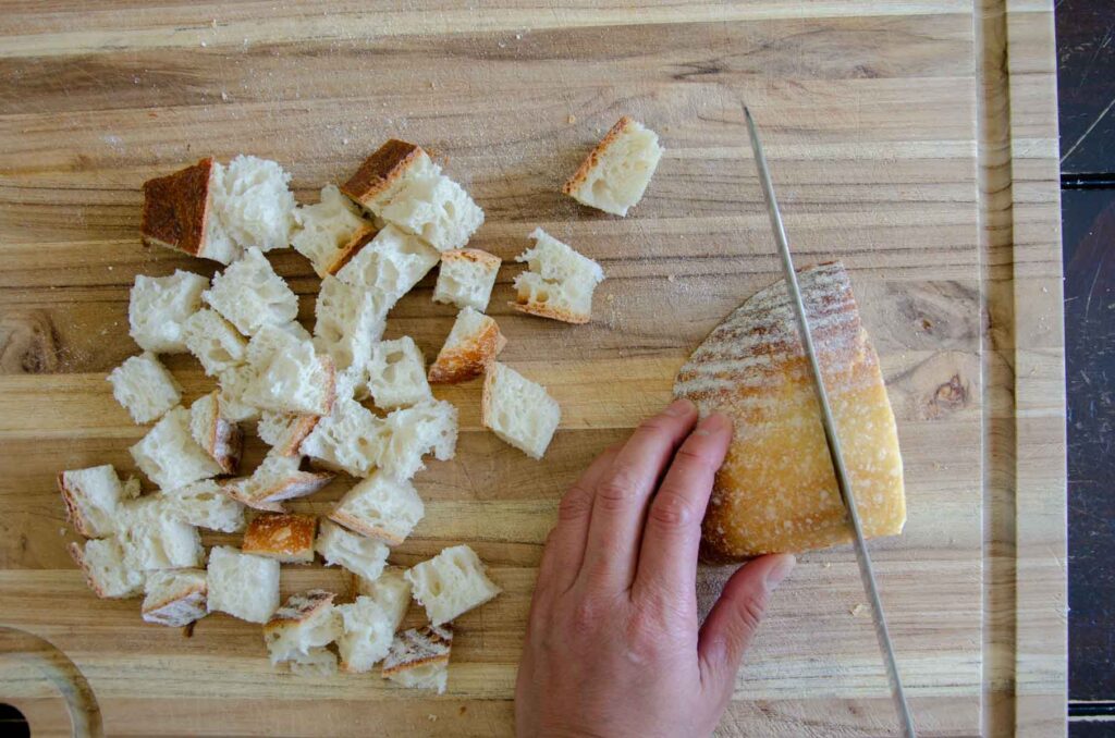 Knife cutting sourdough into cubes