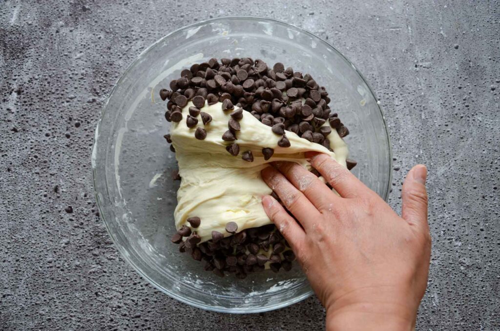 Chocolate chips in bread dough in glass bowl