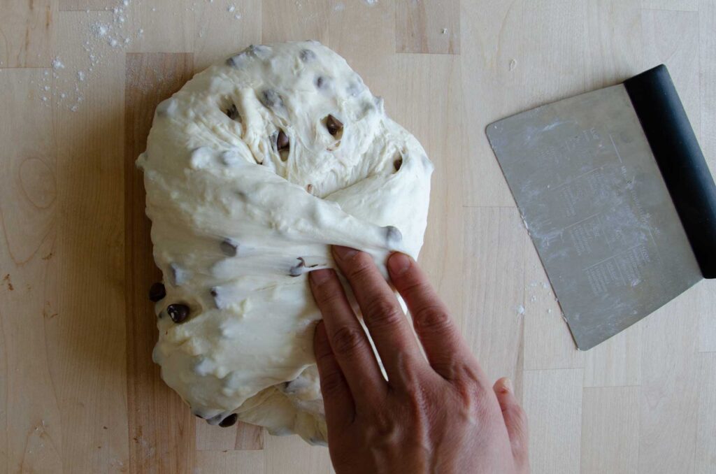 Hand folding dough into center on wood board
