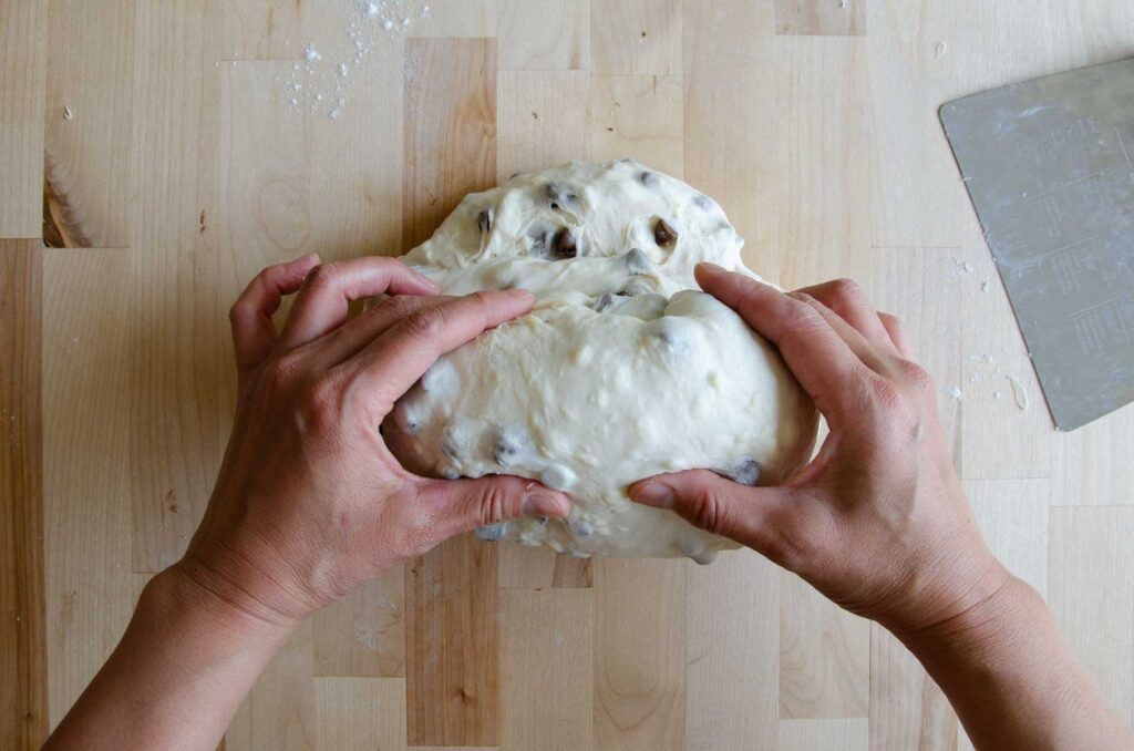 Hands pinching dough on wooden board