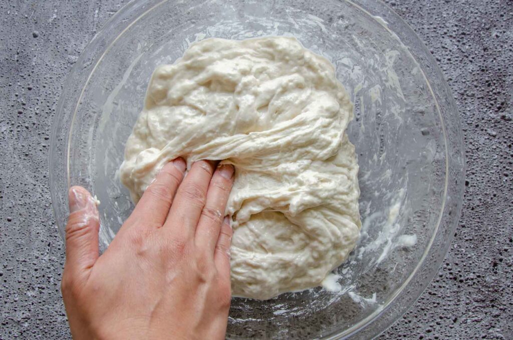 Hand stretching sourdough chocolate chip croissant dough