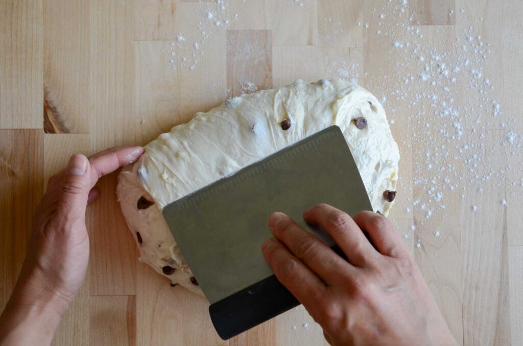Scraper folding dough on wooden board