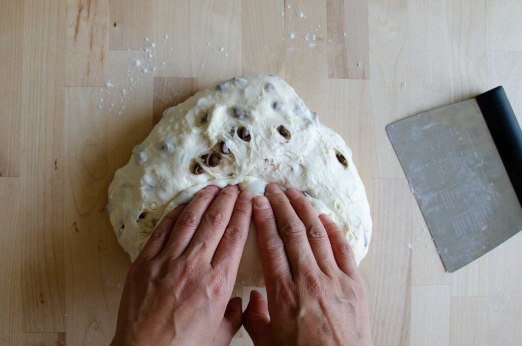 Hands pressing into dough on wood board