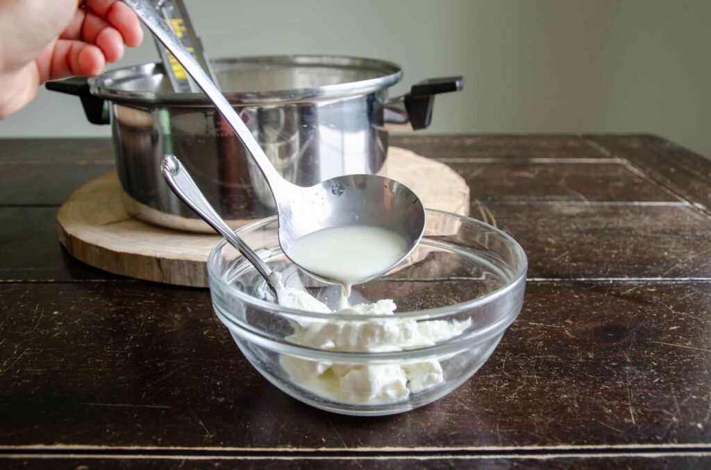Ladling milk into a bowl with yogurt