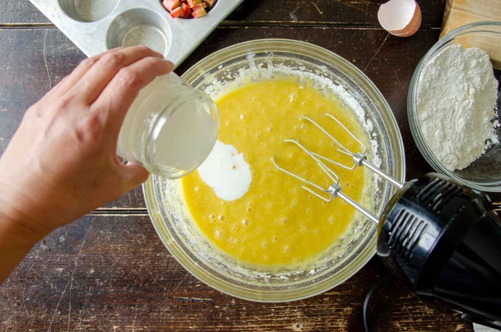 Buttermilk poured into muffin batter by hand