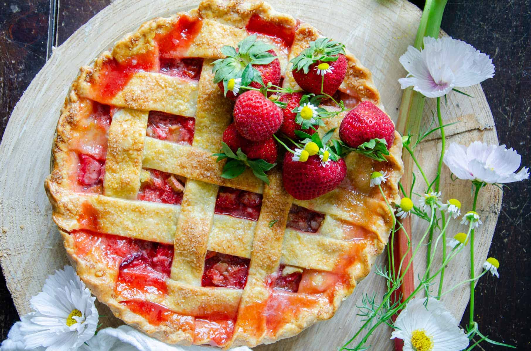 Strawberry rhubarb pie on a wooden circle