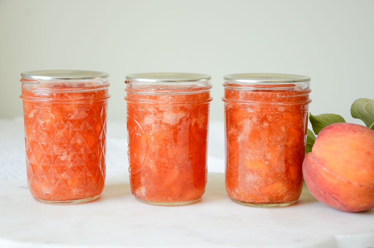 jars of peach jam and a peach