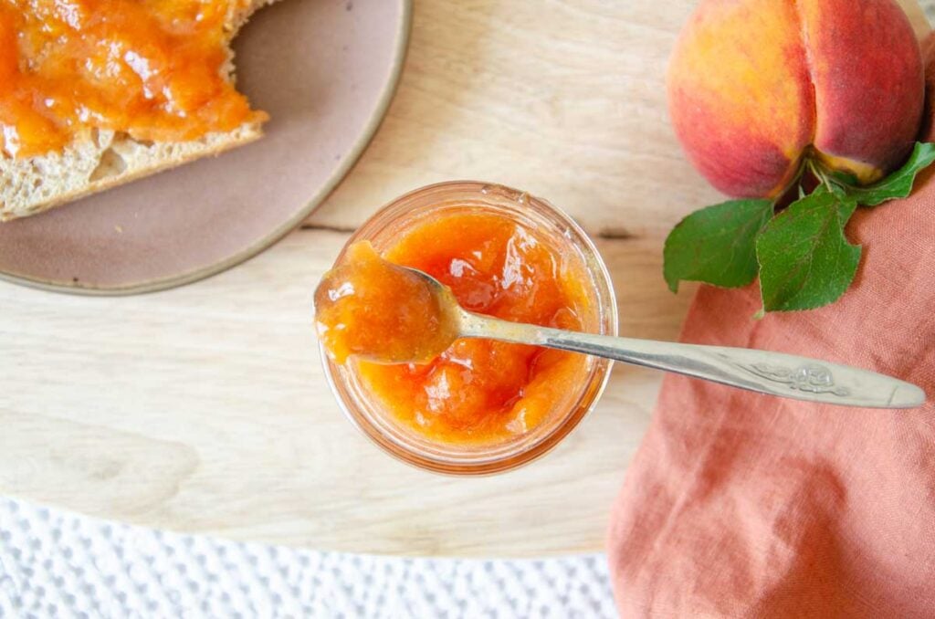 low sugar peach jam in a jar with a small spoon