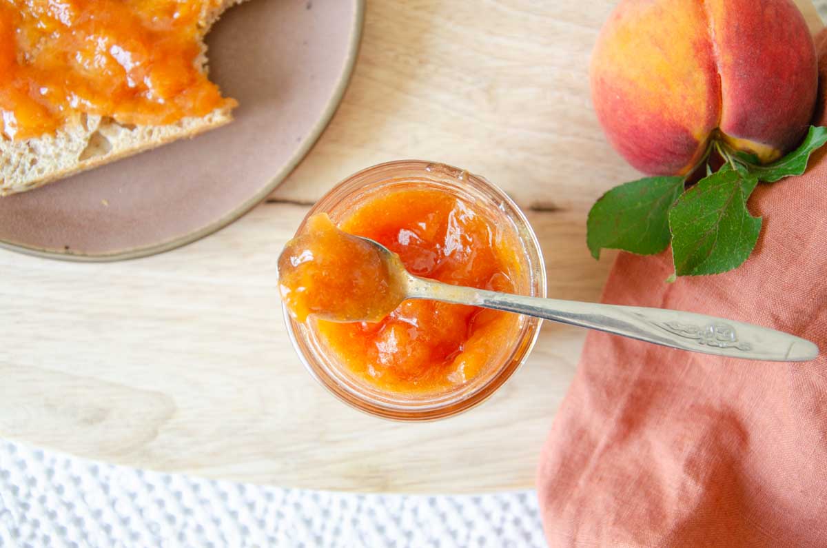 low sugar peach jam in a jar with a small spoon