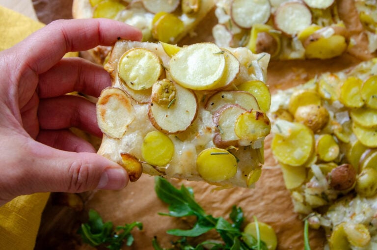 holding a slice of potato pizza