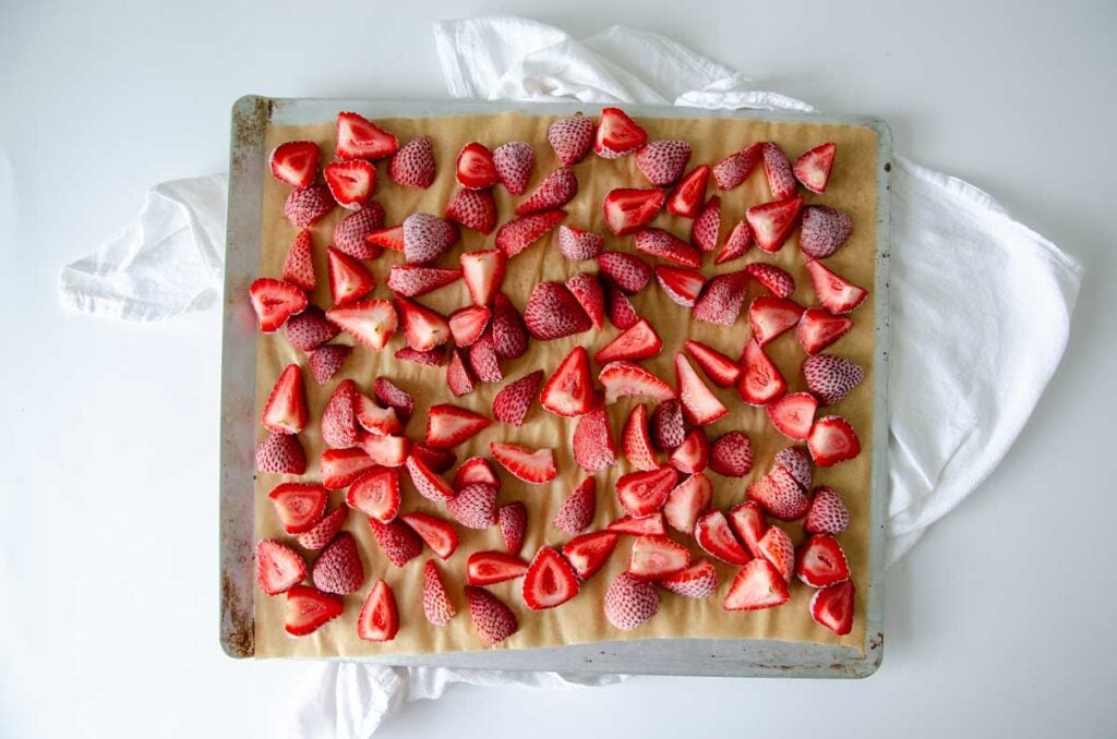 Frozen strawberries on a parchment-lined baking sheet