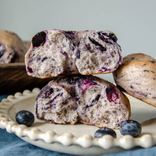 sourdough blueberry bagels torn in half and stacked on top of each other.
