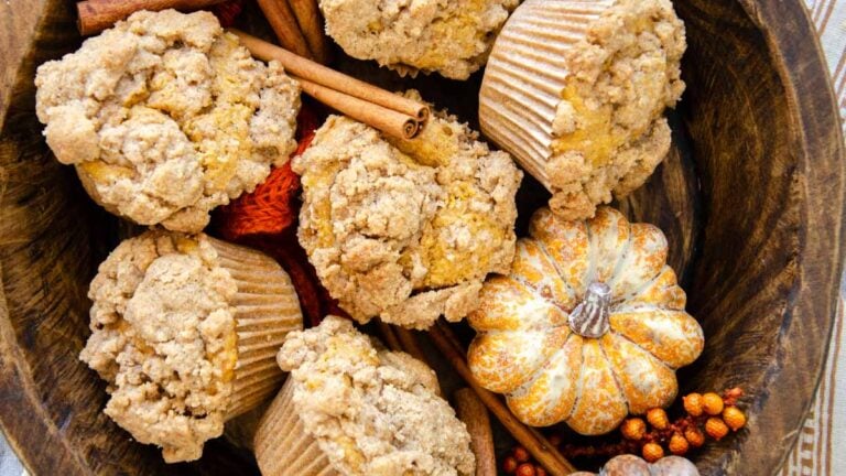 a wood bowl full of sourdough pumpkin muffins and cinnamon sticks