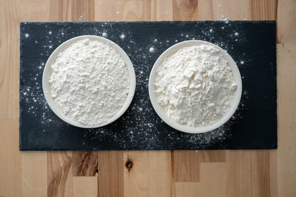 bread flour vs all-purpose flour in bowls on a piece of black slate