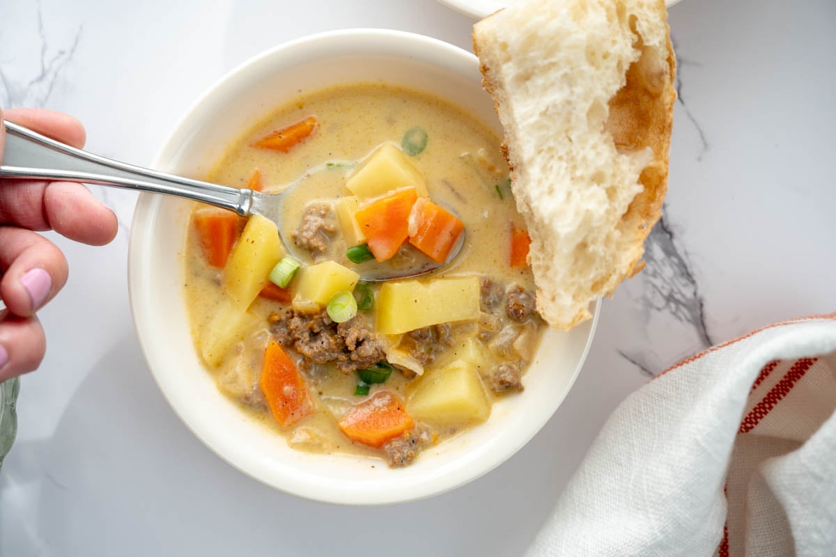 a bowl of cheeseburger soup with a piece of sourdough bread