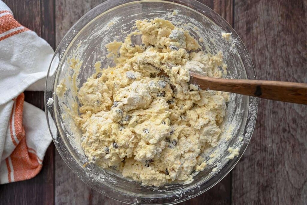 sourdough Irish soda bread dough in a glass bowl with wooden spoon