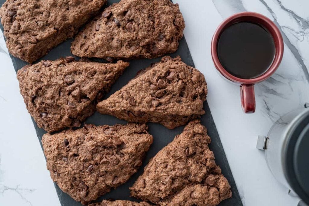 sourdough chocolate chip scones on a piece of black slate, with a cup of coffee