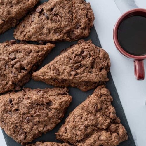 sourdough chocolate chip scones on a piece of black slate, with a cup of coffee