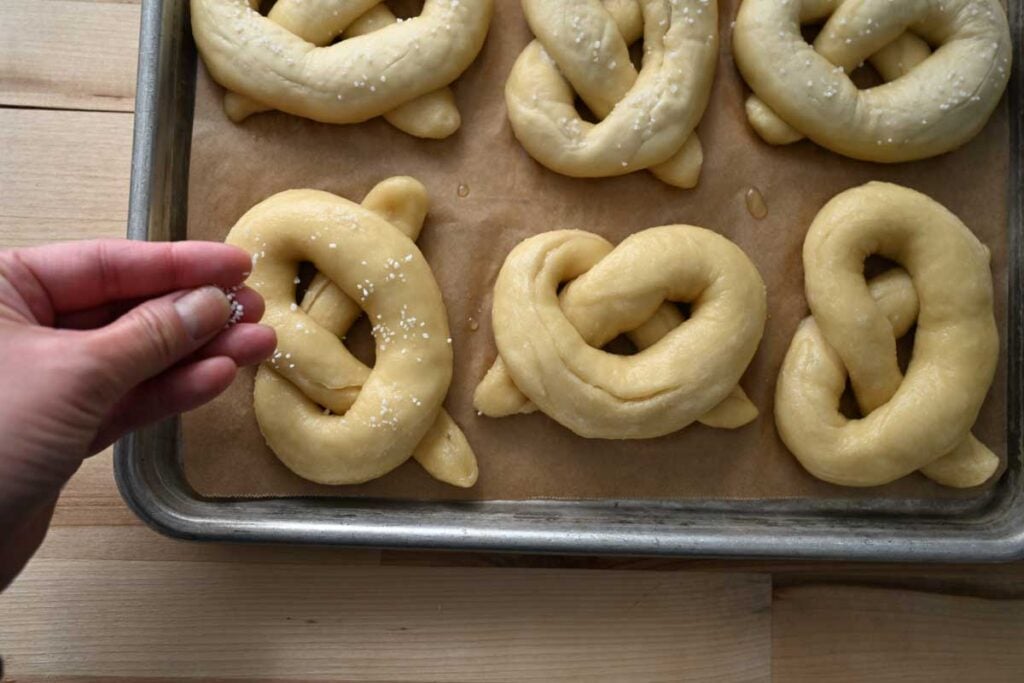sprinkling salt on the boiled pretzels