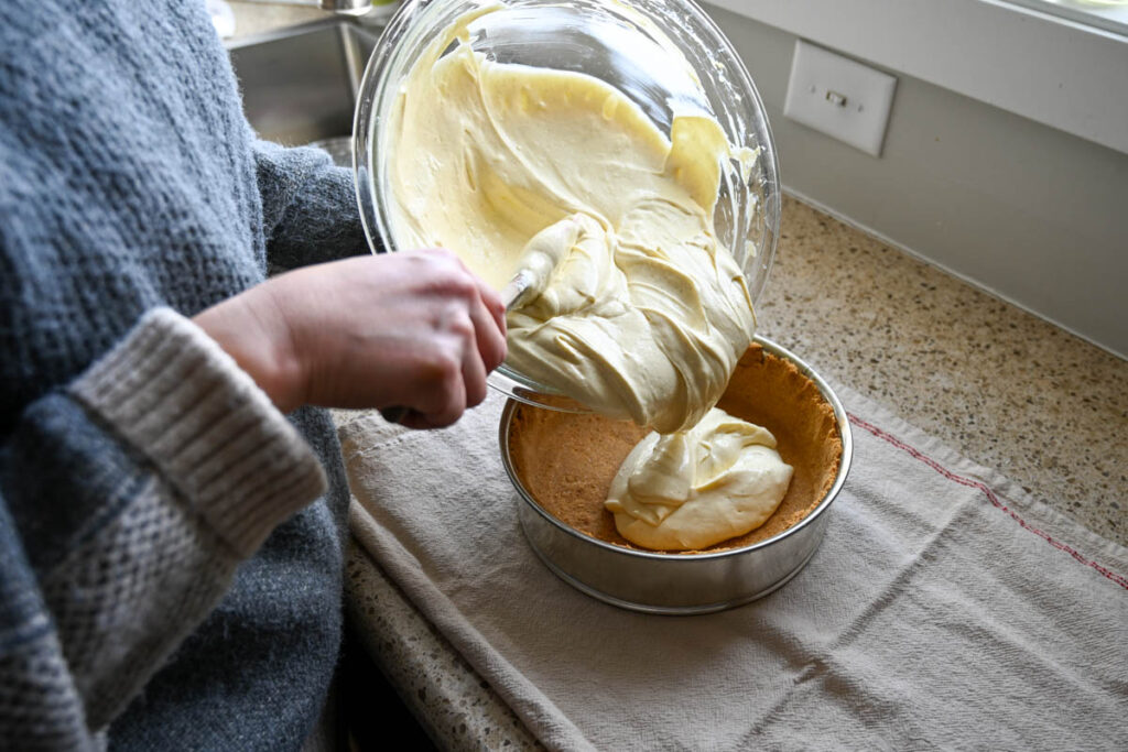 pouring easy cheesecake filling into graham cracker crust