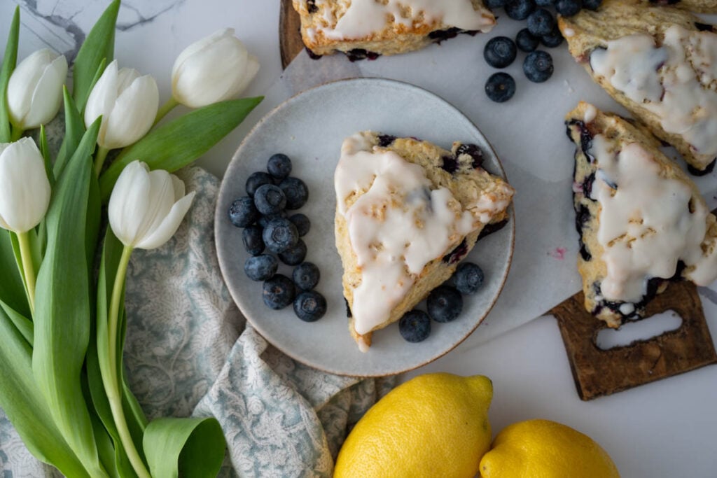 lemon blueberry sourdough scone on a plate with tulips