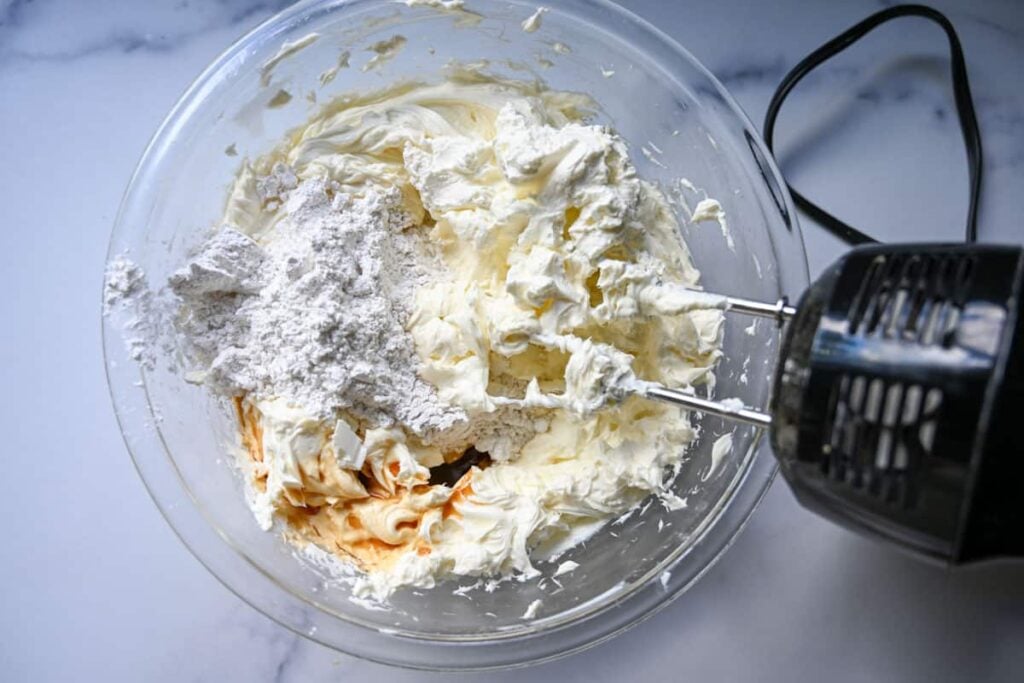 mixing the no bake cheesecake ingredients in a glass bowl