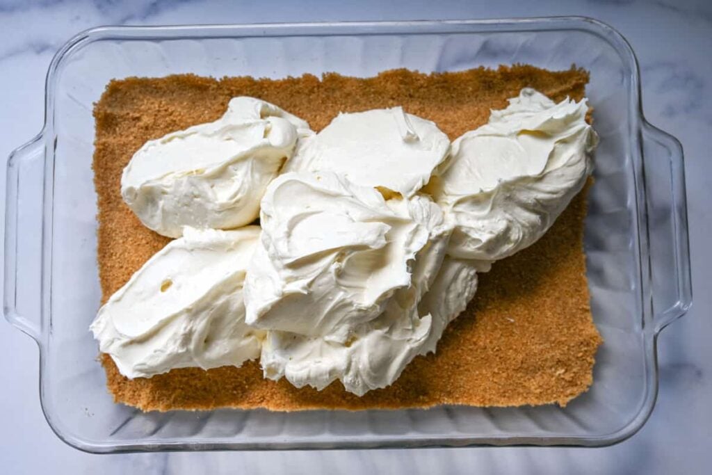 dolloping the cheesecake filling mixture on to the graham cracker crust 