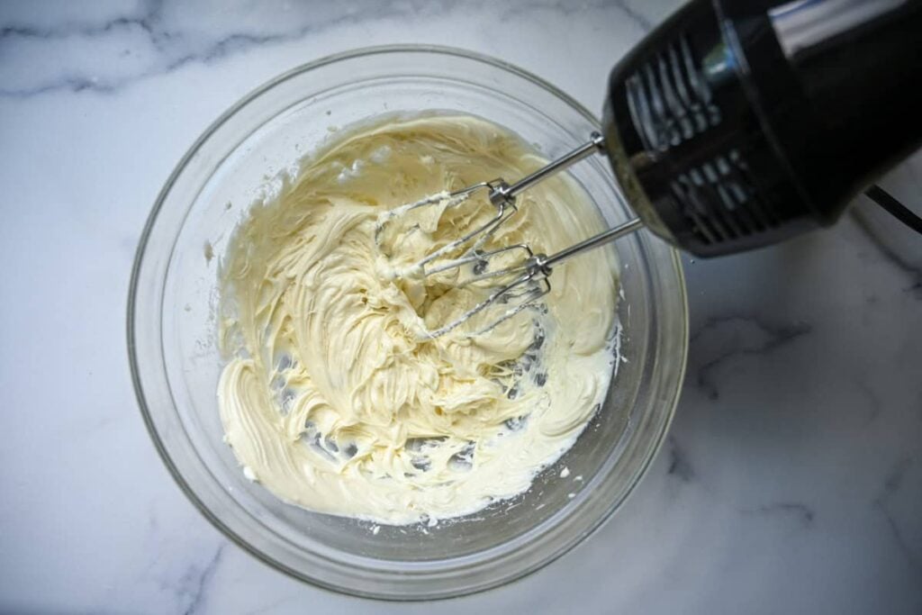 creaming cream cheese in a bowl with electric mixer
