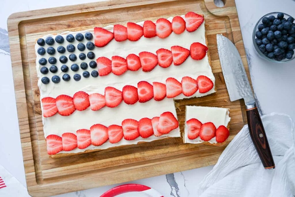 sourdough flag fruit pizza with a piece cut from it on a wooden board