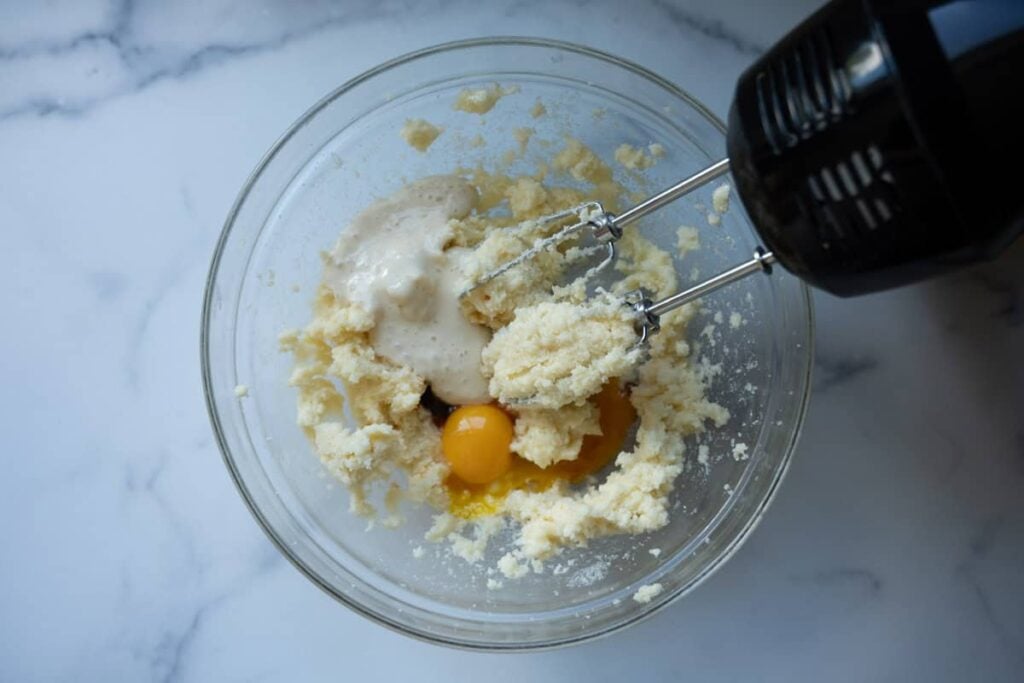 adding egg yolks, vanilla extract, and sourdough discard in glass bowl