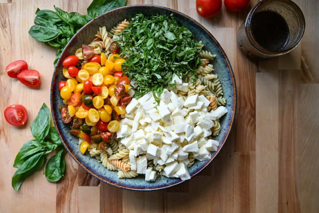 pasta with cut tomatoes, basil and fresh mozzarella cheese in a large bowl