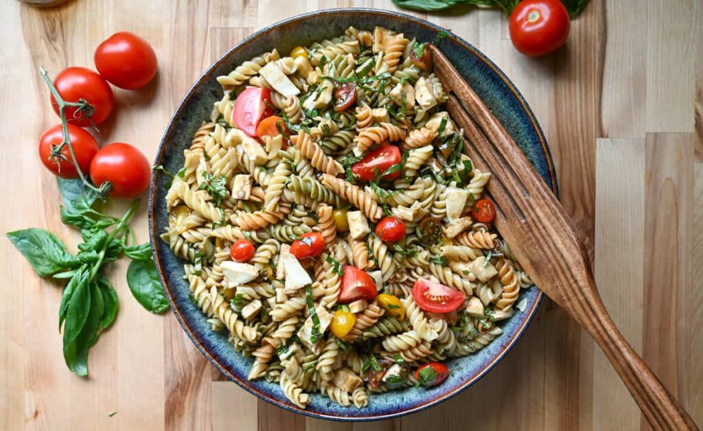 Easy caprese pasta salad in a large bowl with a wood serving spoon