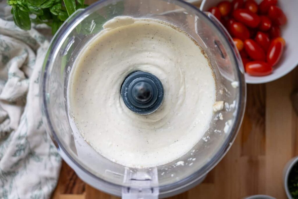 whipped herbed ricotta cheese in the bowl of a food processor