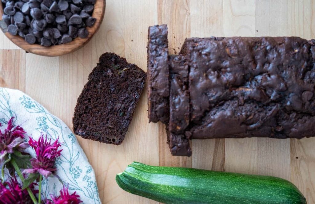 sliced sourdough chocolate zucchini bread with chocolate chips and zucchini next to it