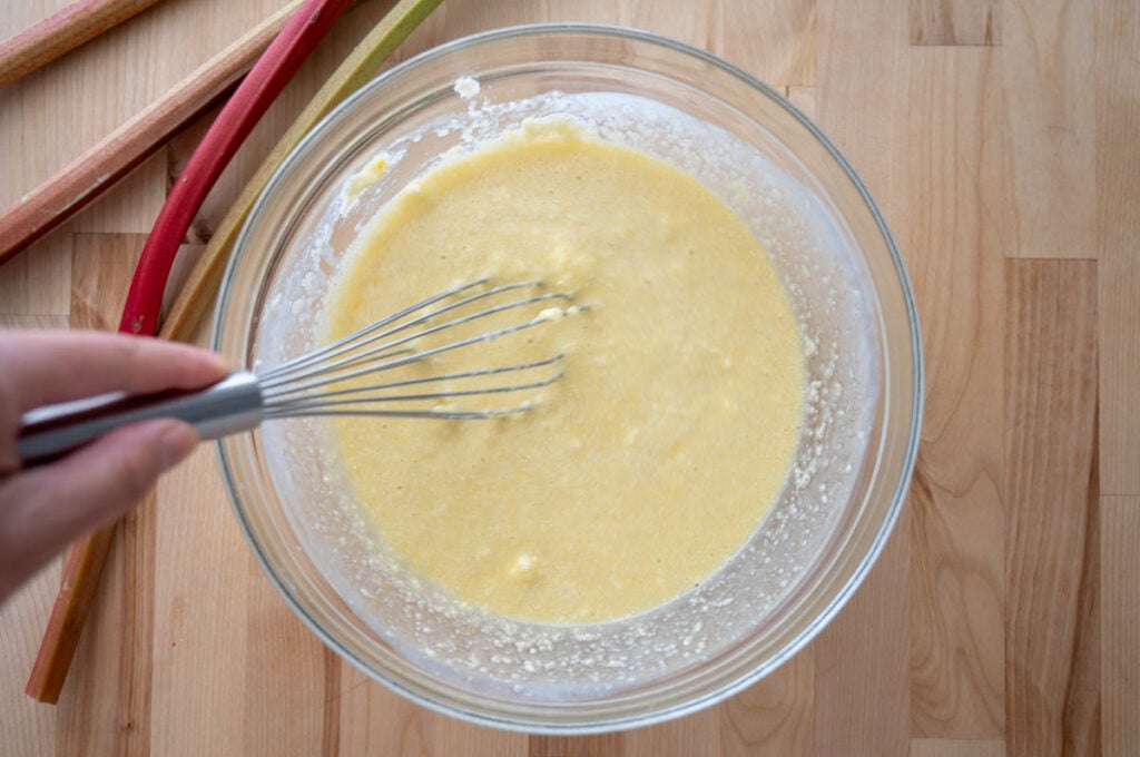 mixing sourdough rhubarb bread wet ingredients in a glass bowl