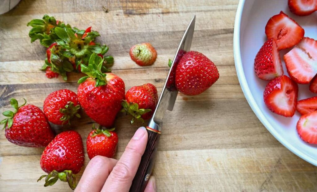 cutting strawberries on a wooden cutting board