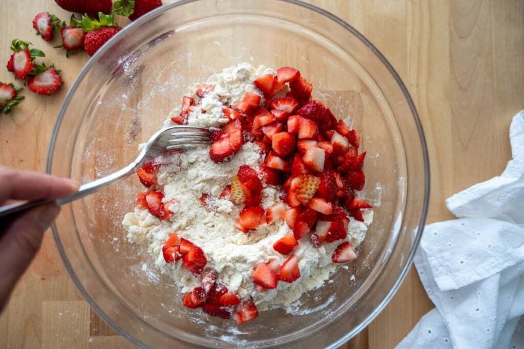 tossing strawberry pieces into dry ingredients for sourdough strawberry scone