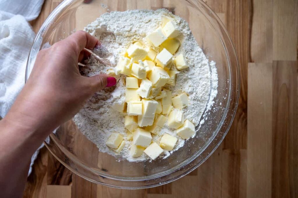 adding butter cubes into flour mixture for sourdough shortcake