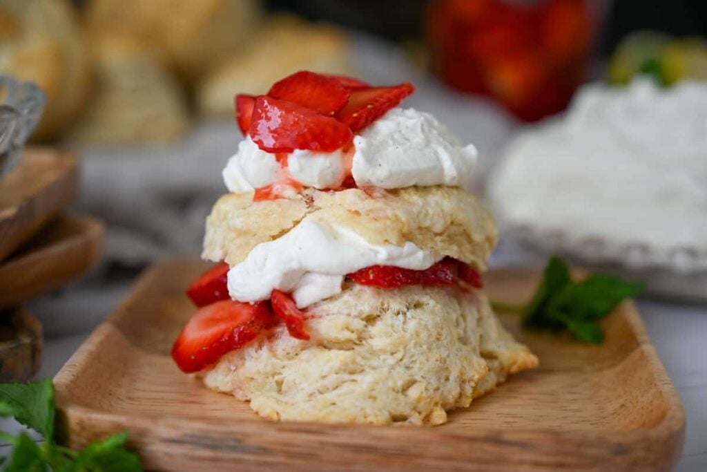 sourdough strawberry shortcake with strawberries and whipped cream on a wood plate