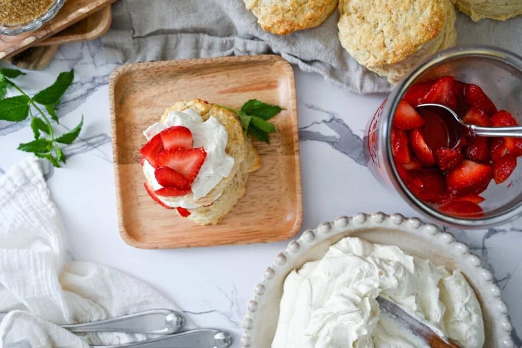 sourdough strawberry shortcake with strawberries and whipped cream on a wood plate
