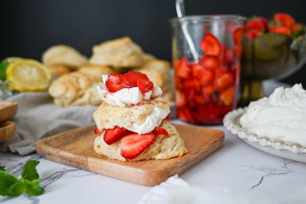 sourdough strawberry shortcake with strawberries and whipped cream on a wood plate