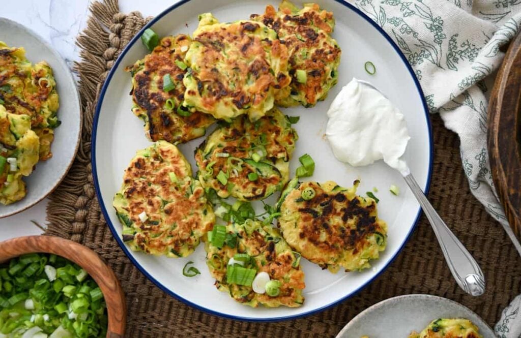 sourdough zucchini fritters on a plate with a dollop of sour cream