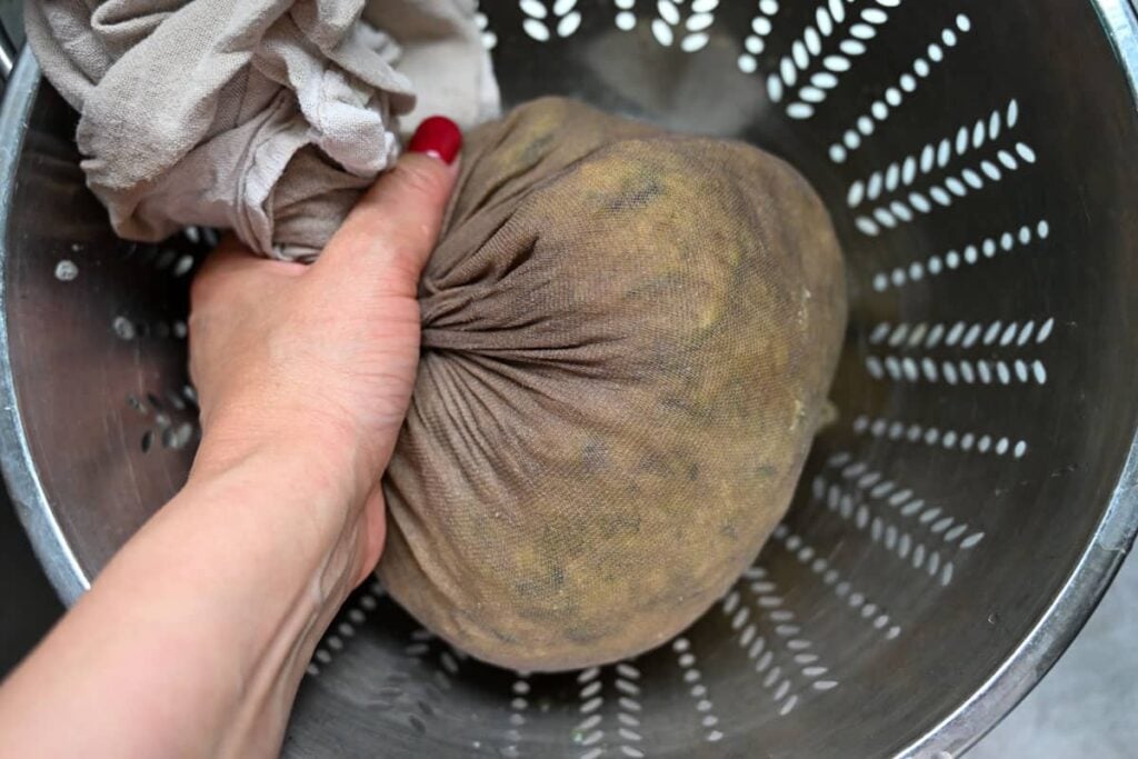 squeezing the excess water content from grated zucchini in a clean dish towel 