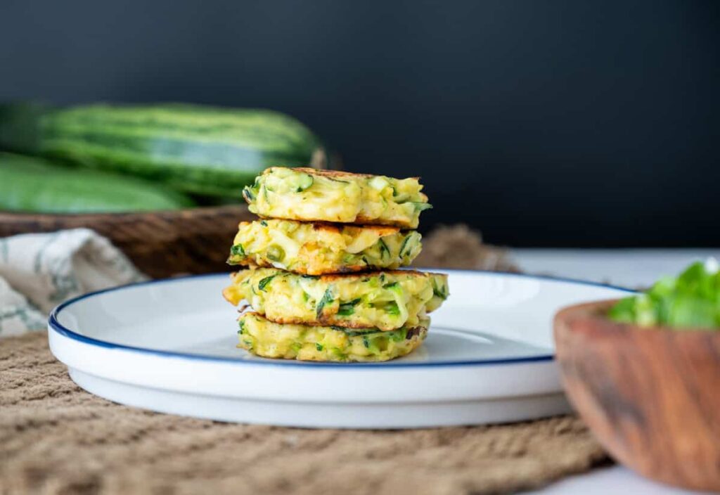 sourdough zucchini fritters stacked on top on another on a plate