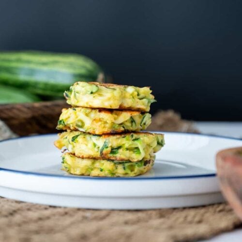sourdough zucchini fritters stacked on top on another on a plate