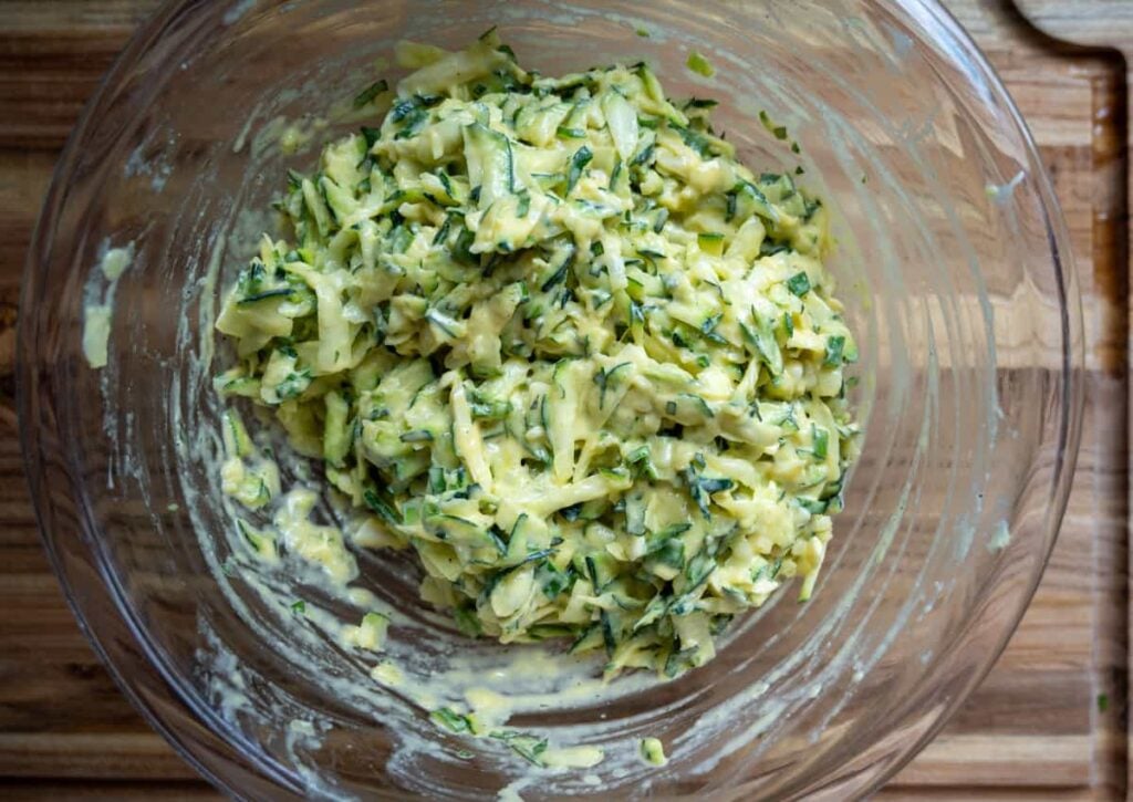 sourdough zucchini fritter mixture in a large glass mixing bowl