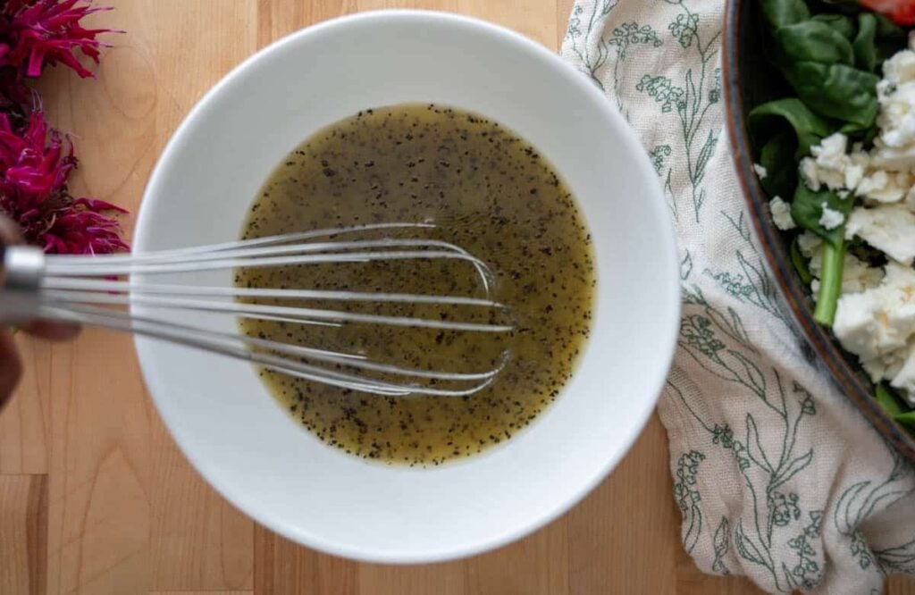 mixing poppyseed vinaigrette in a small bowl
