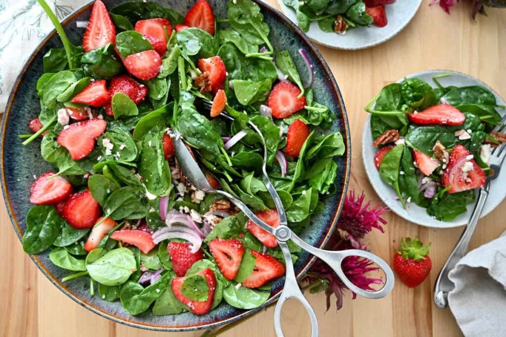 strawberry spinach salad in a large bowl with salad tongs